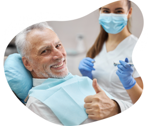 A man smiling and holding his thumb up as he is sitting next to a female dental hygienist