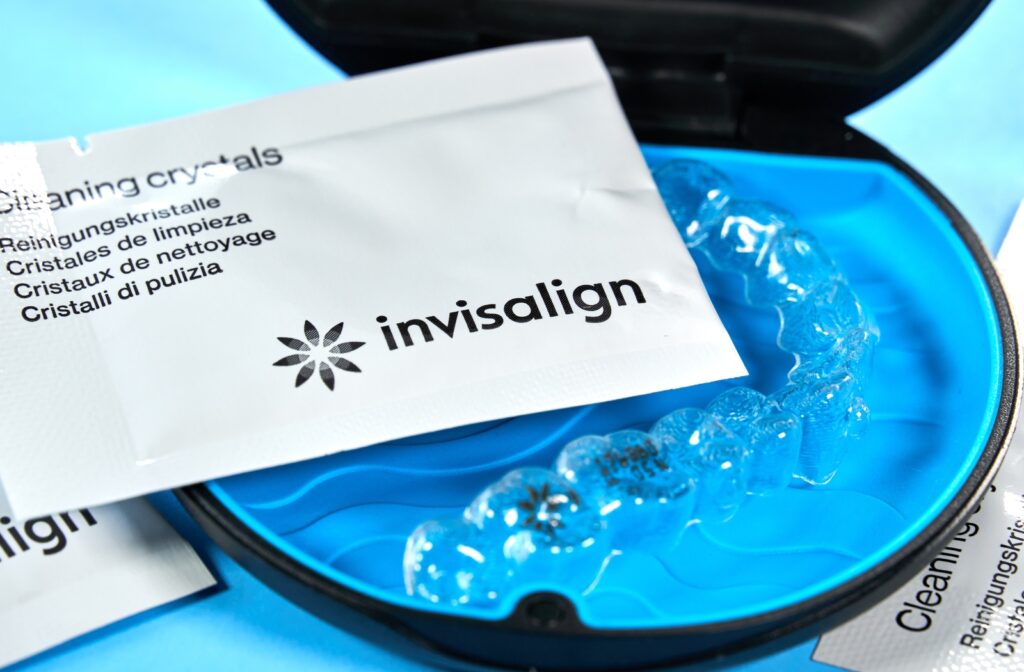 Image showing an open circular Invisalign case with a set of aligners, and a several packets of cleaning crystals.