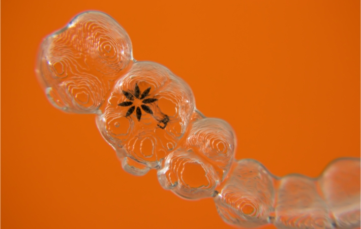 Close up image of a set of Invisalign aligners showing the custom detail with printed Invisalign logo.