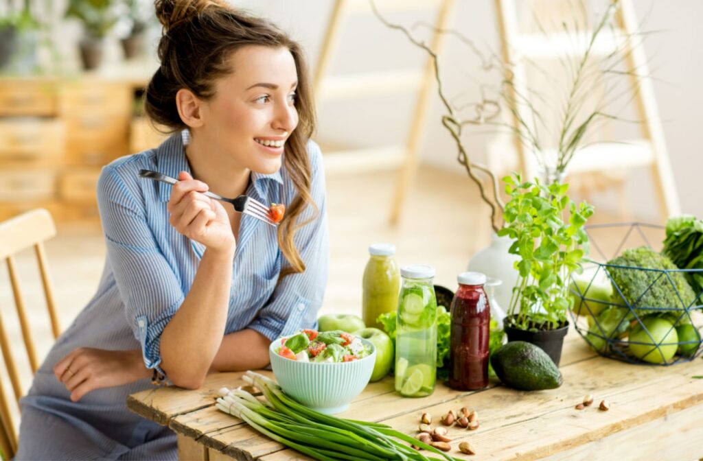 A young woman eating a salad at her kitchen table