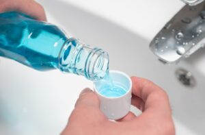Close-up of man’s hand pouring a bottle of mouthwash into cap