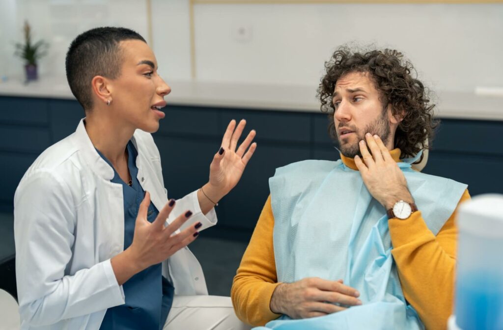 A patient with tooth sensitivity listens intently  to their friendly dentist explain how to treat their tooth sensitivity