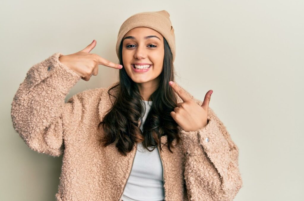 A smiling person points at their teeth after a dental freezing.