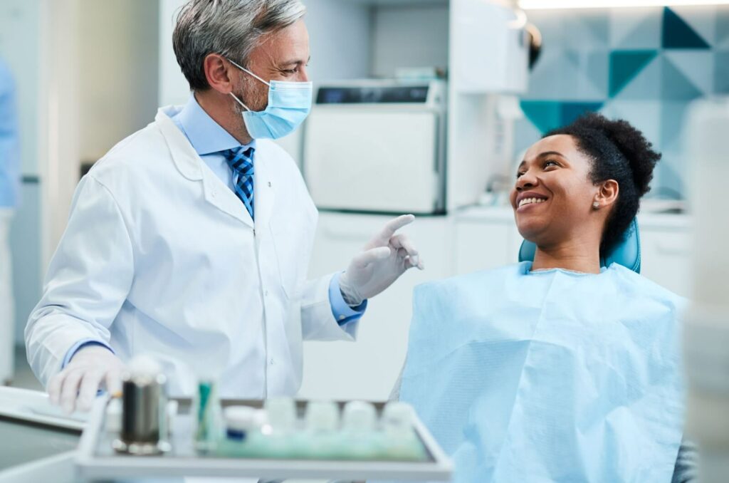 A dentist talks to their patient before a dental procedure.