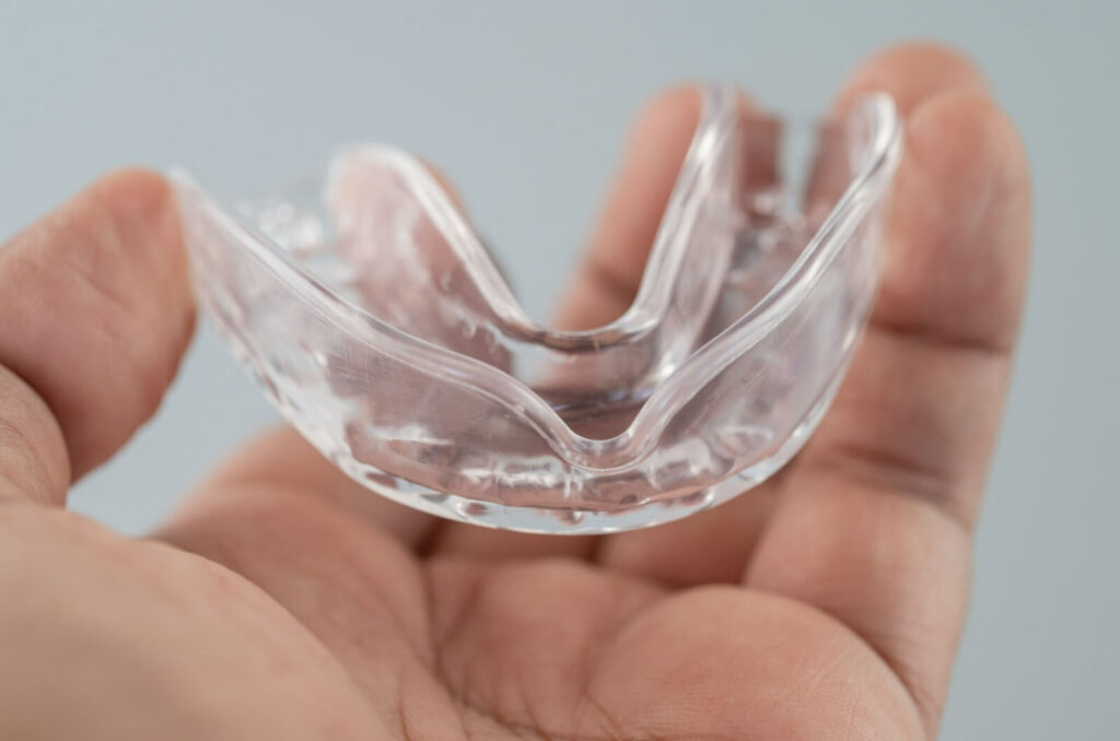 A closeup of a hand holding a custom-made mouth guard to prevent teeth grinding.