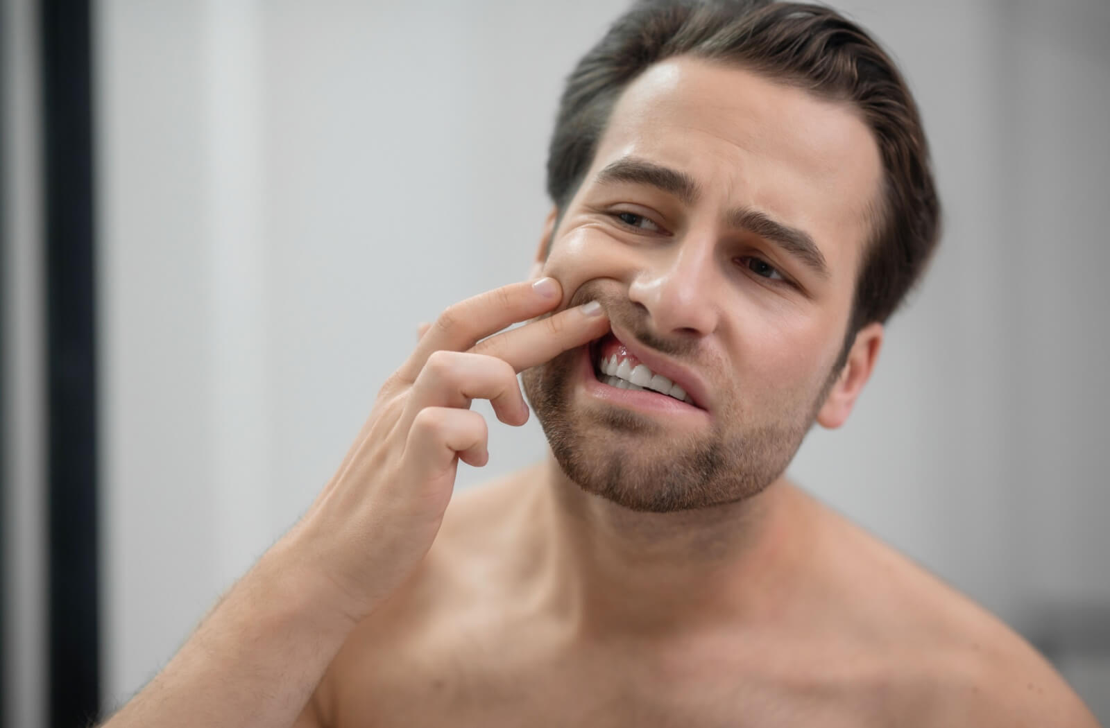 A person checks their gum health in their bathroom mirror.