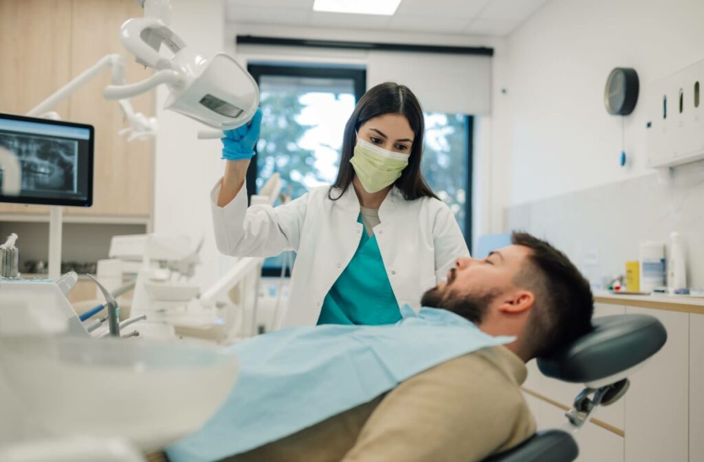 A dental professional adjusts a light while a patient lies in a chair, preparing for a root canal procedure.