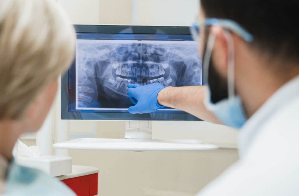 Dentist pointing at a dental X-ray on a screen.