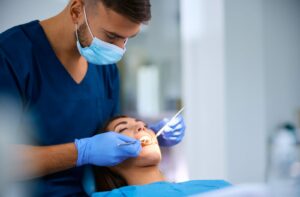 Patient laying back on a dental chair getting a recall exam from a hygienist