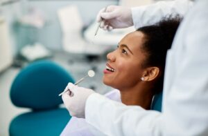 Dentist performing a routine dental exam as a patient relaxes in the dental chair.